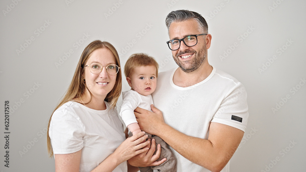 Family of mother, father and baby smiling together looking a the camera over isolated white background