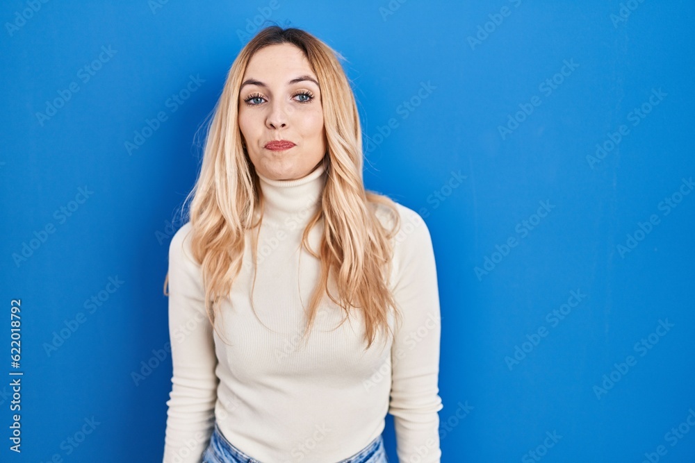 Young caucasian woman standing over blue background smiling looking to the side and staring away thinking. Young caucasian woman standing over blue background smiling looking to the side and staring away thinking.