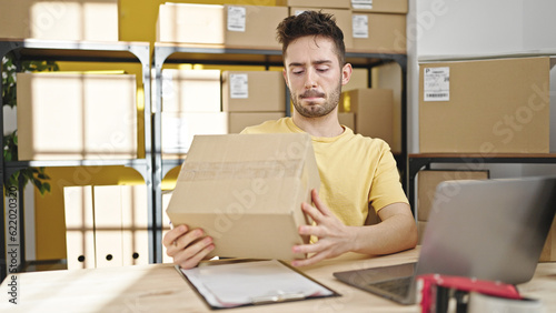 Young hispanic man ecommerce business worker holding package at office