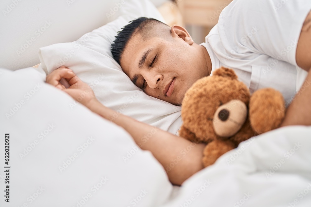 Young latin man hugging teddy bear lying on bed sleeping at bedroom Young latin man hugging teddy bear lying on bed sleeping at bedroom