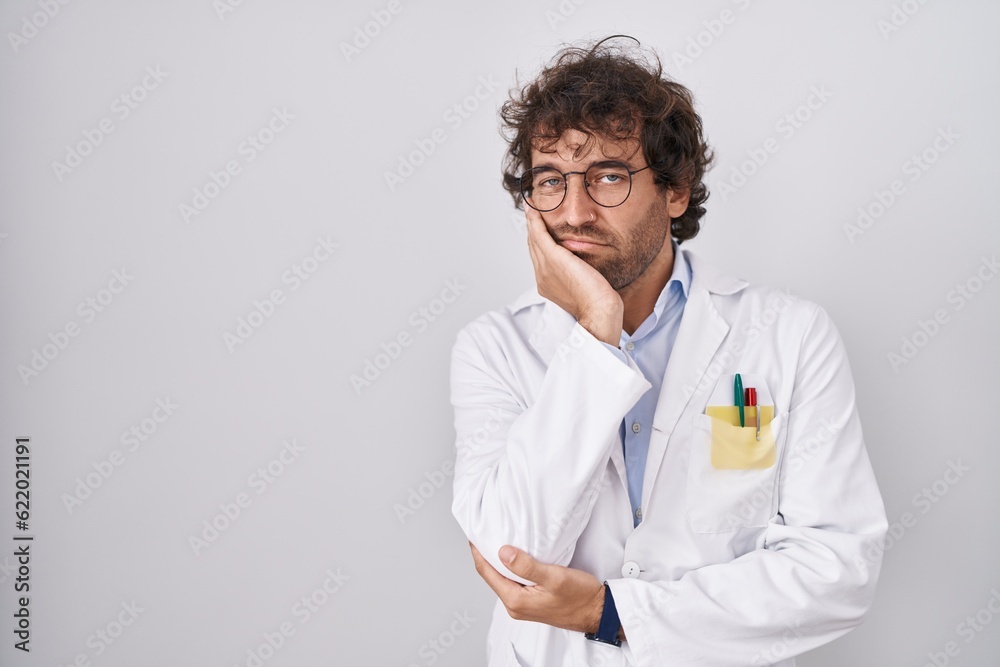 Hispanic young man wearing doctor uniform thinking looking tired and bored with depression problems with crossed arms. Hispanic young man wearing doctor uniform thinking looking tired and bored with depression problems with crossed arms.