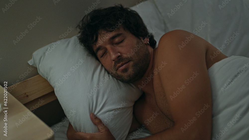 Young hispanic man lying on bed sleeping shirtless at bedroom