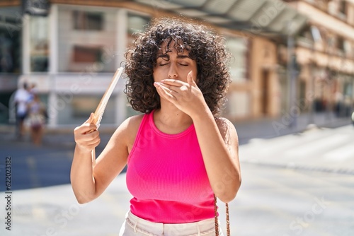 Young middle eastern woman using handfan suffering for hot at street photo