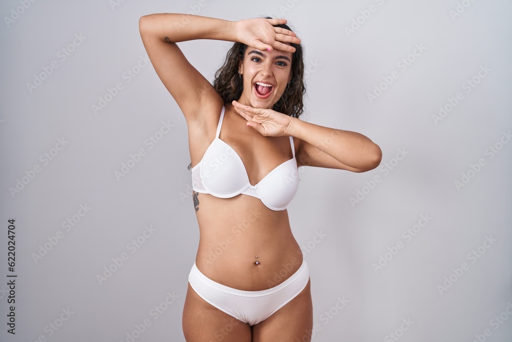 Young hispanic woman wearing white lingerie smiling cheerful playing peek a boo with hands showing face. surprised and exited