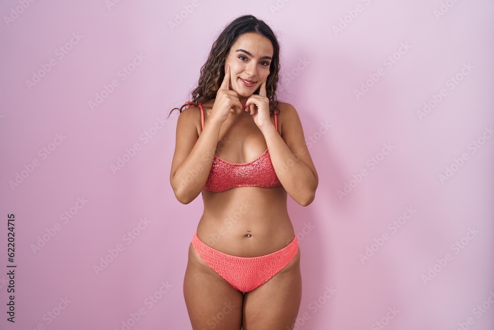 Young hispanic woman wearing lingerie over pink background smiling with open mouth, fingers pointing and forcing cheerful smile Young hispanic woman wearing lingerie over pink background smiling with open mouth, fingers pointing and forcing cheerful smile
