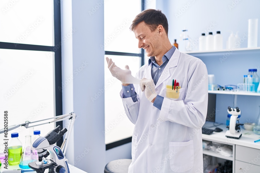 Young man scientist smiling confident wearing gloves at laboratory Young man scientist smiling confident wearing gloves at laboratory