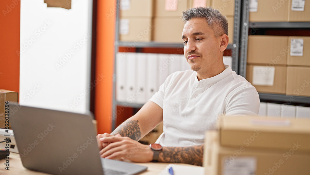 Young hispanic man ecommerce business worker using laptop at office Young hispanic man ecommerce business worker using laptop at office