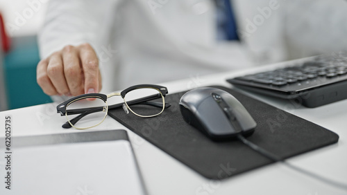 Young hispanic man doctor using computer working at clinic
