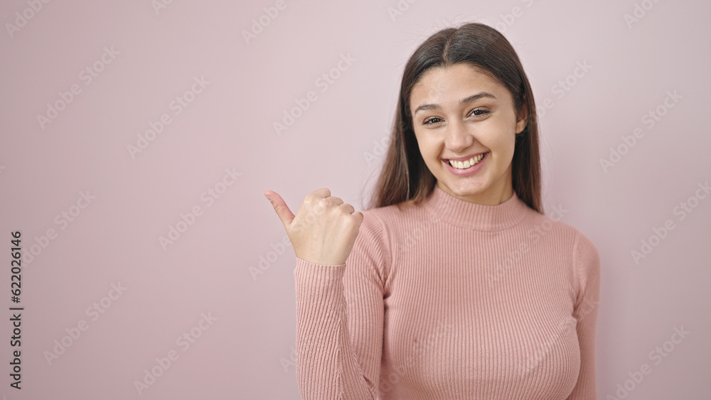 Young beautiful hispanic woman smiling pointing to the side over isolated pink background Young beautiful hispanic woman smiling pointing to the side over isolated pink background