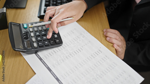Young beautiful hispanic woman business worker using calculator accounting at office