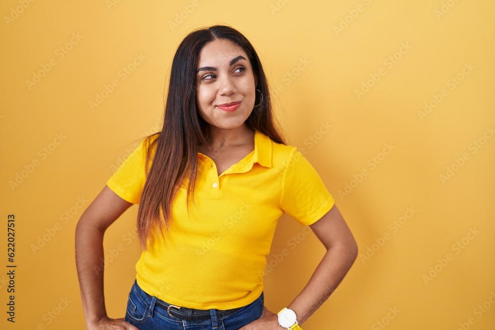 Obraz premium Young arab woman standing over yellow background smiling looking to the side and staring away thinking.