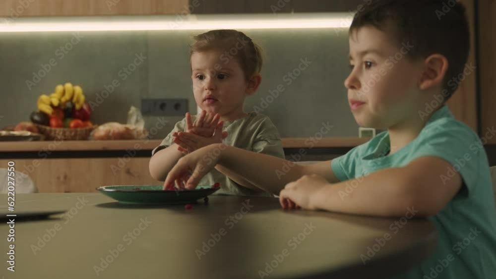 Push in scene of a brother and sister sisint at the dining table and eating pomegranate Push in scene of a brother and sister sisint at the dining table and eating pomegranate