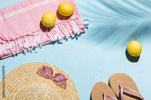 Photography Summer flat lay with sunglasses, straw hat and beach accessories on blue background with palm leaf shadow, sun and sunlight