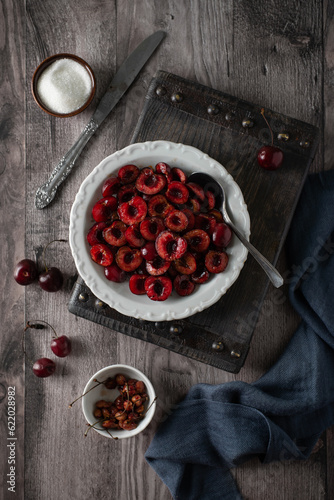 Sweet cherries in white plate on a wooden board on a wooden background. Top view