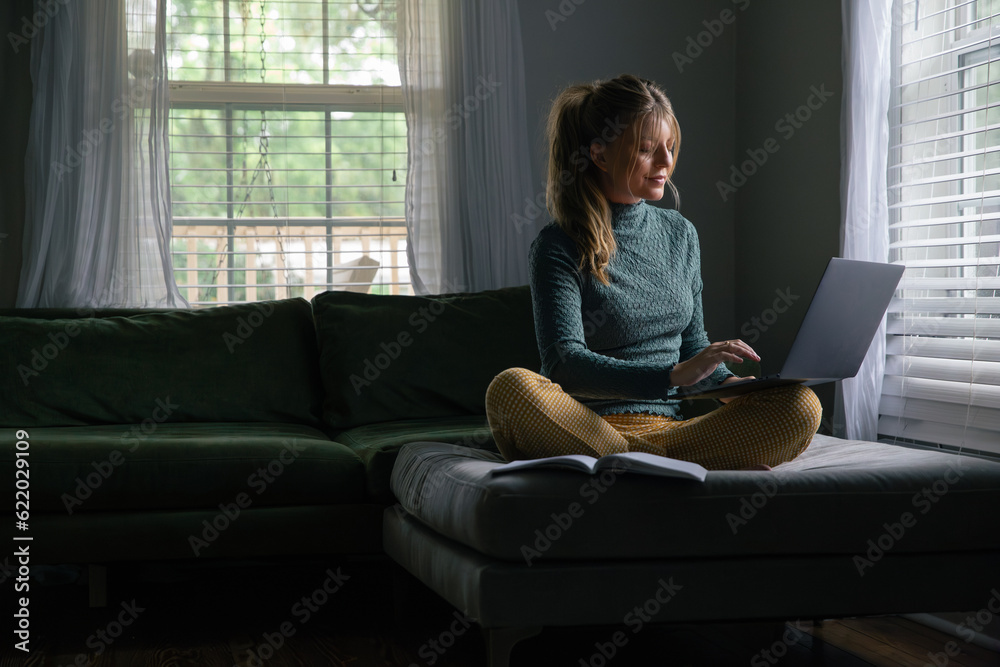Business Woman Work from Home on Laptop Computer, Remote Employee Worker, Sitting in Living Room of House. Looking at screen with grin. Business Woman Work from Home on Laptop Computer, Remote Employee Worker, Sitting in Living Room of House. Looking at screen with grin.