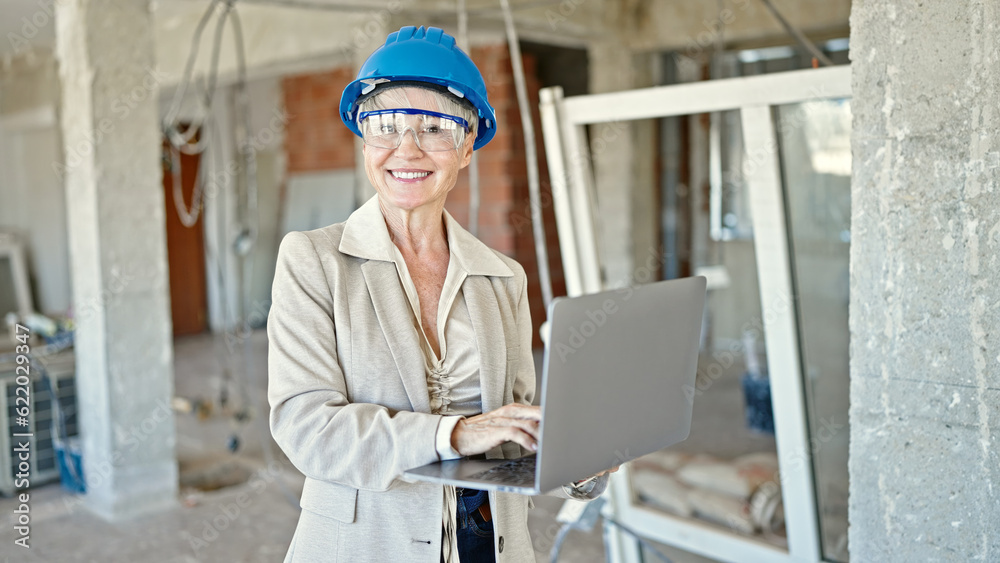 Middle age blonde woman architect smiling confident using laptop at construction site Middle age blonde woman architect smiling confident using laptop at construction site