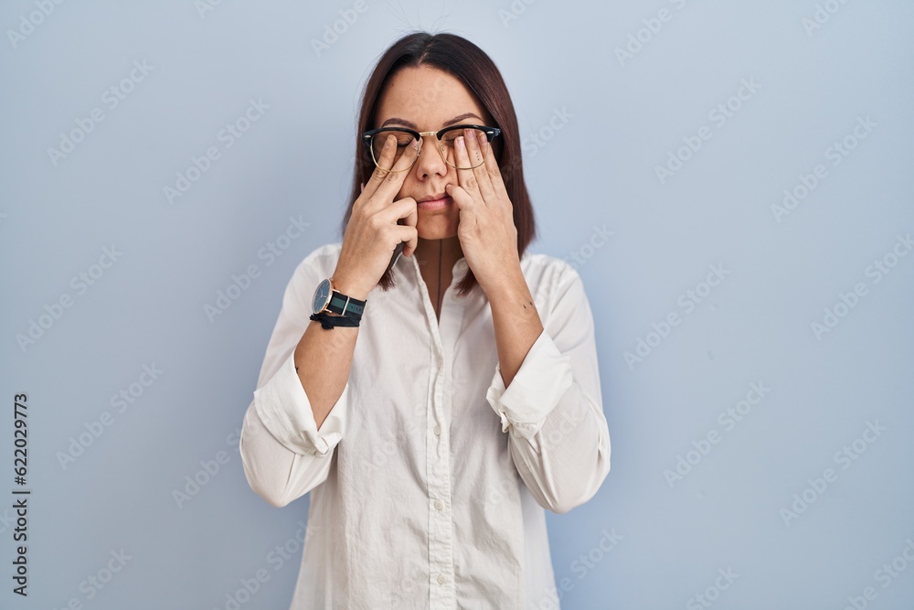 Young hispanic woman standing over white background rubbing eyes for fatigue and headache, sleepy and tired expression. vision problem Young hispanic woman standing over white background rubbing eyes for fatigue and headache, sleepy and tired expression. vision problem