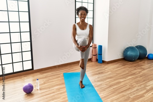 African american woman smiling confident stretching leg at sport center