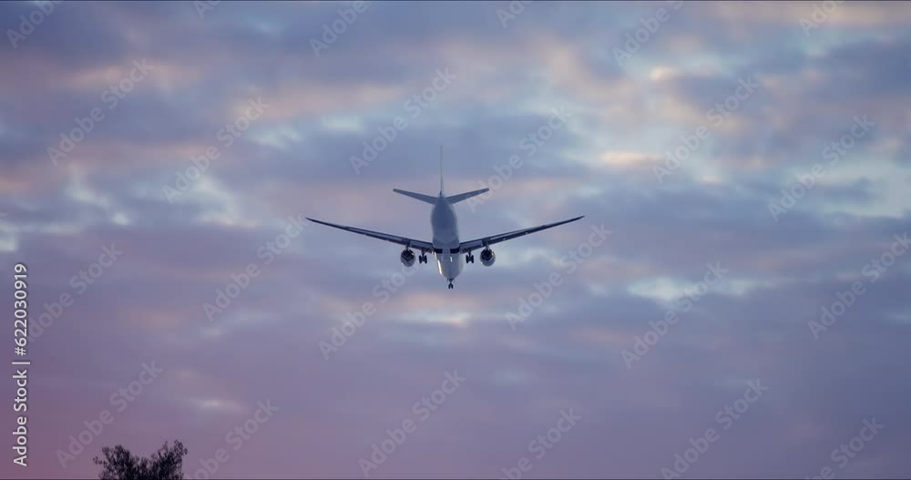 Large airliner with passengers on blue sky is landingat airport of bright orange sunset on sunny summer day. Go Everywhere. Airplane flies in sky at sunset day lens flares. Travel Large airliner with passengers on blue sky is landingat airport of bright orange sunset on sunny summer day. Go Everywhere. Airplane flies in sky at sunset day lens flares. Travel