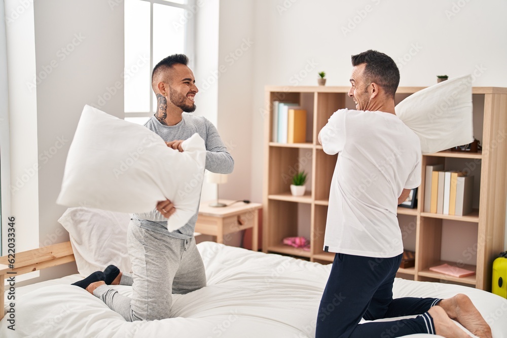 Obraz premium Two men couple fighting with pillows at bedroom