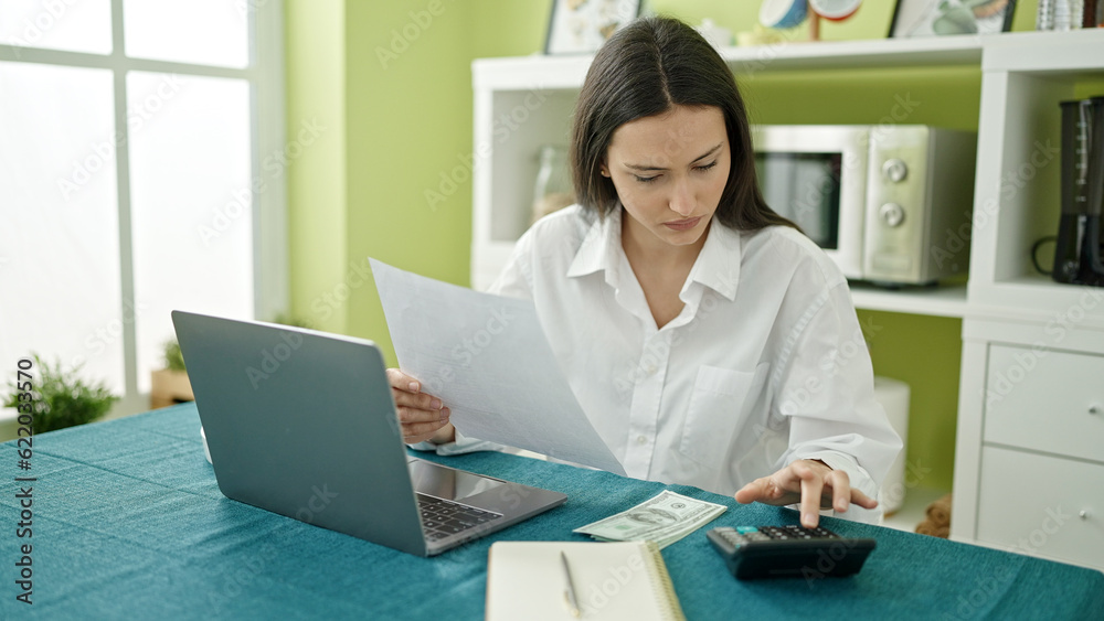 Young beautiful hispanic woman using laptop accounting at dinning room Young beautiful hispanic woman using laptop accounting at dinning room