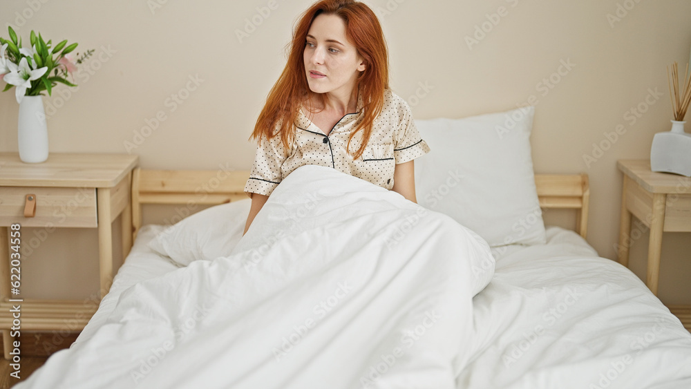 Young redhead woman sitting on bed with relaxed expression at bedroom Young redhead woman sitting on bed with relaxed expression at bedroom