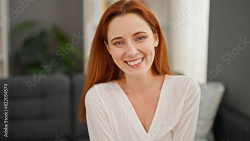 Free Download Young redhead woman smiling confident sitting on sofa at home - GFXLoad