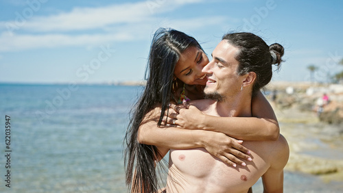 Man and woman tourist couple hugging each other smiling at beach