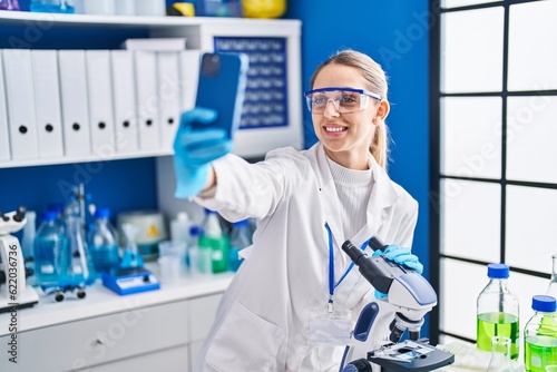 Young woman scientist smiling confident make selfie by smartphone at laboratory