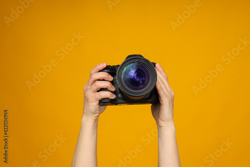 Close-up of a camera in hands on a yellow background