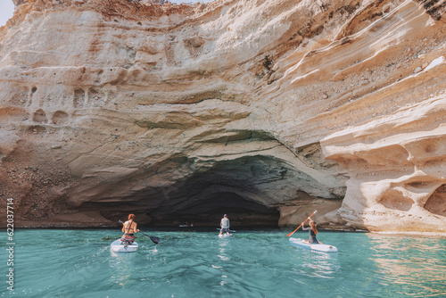 Group of sup boarders enters huge limestone cave on a sea coast
