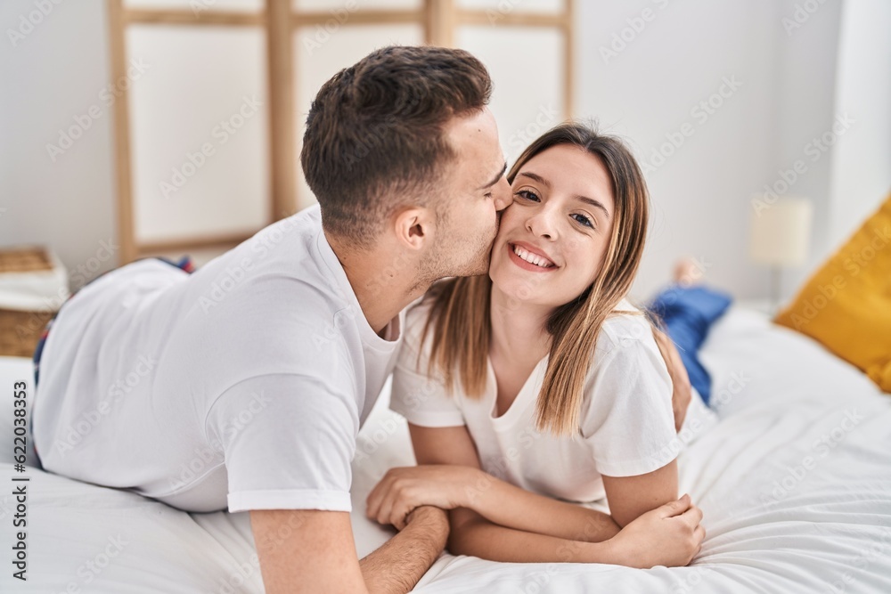 Man and woman couple lying on bed hugging each other and kissing at bedroom Man and woman couple lying on bed hugging each other and kissing at bedroom