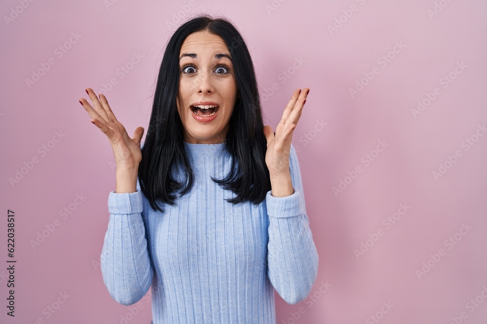 Hispanic woman standing over pink background celebrating crazy and amazed for success with arms raised and open eyes screaming excited. winner concept Hispanic woman standing over pink background celebrating crazy and amazed for success with arms raised and open eyes screaming excited. winner concept