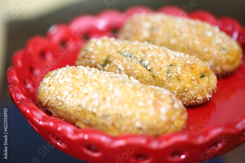 Sabores do mar em uma linda apresentação! Croquete de camarão servido em uma travessa de louça vermelha, decorado com ramos de tomilho. Uma delícia imperdível para um evento descontraído. photo