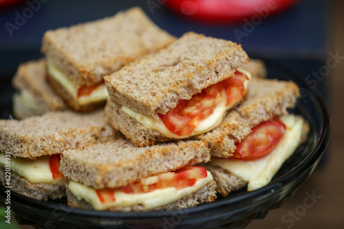 Lanche saudável de pão integral, queijo e tomate, delicadamente montado em uma apresentação colorida, perfeito para desfrutar em um evento especial. photo