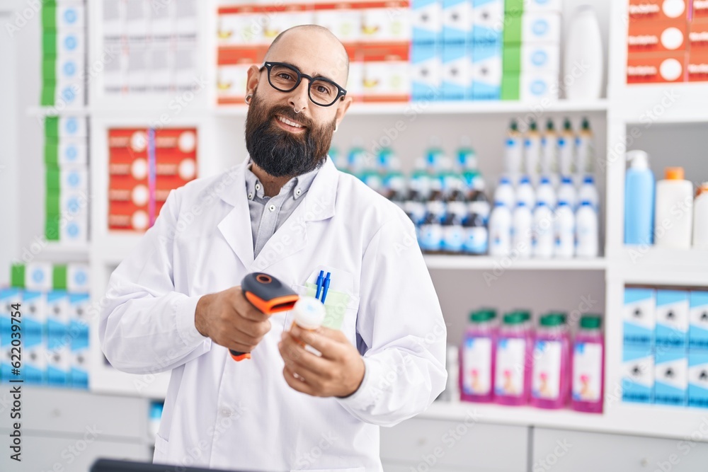 Young bald man pharmacist scanning pills bottle at pharmacy