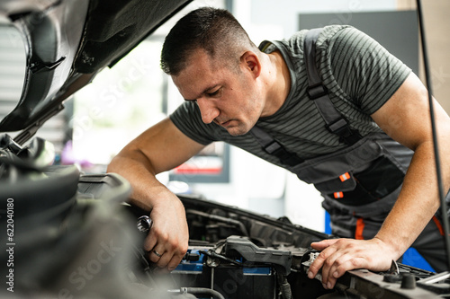  young mechanic in workshop repairs car engine with key © Nemanja