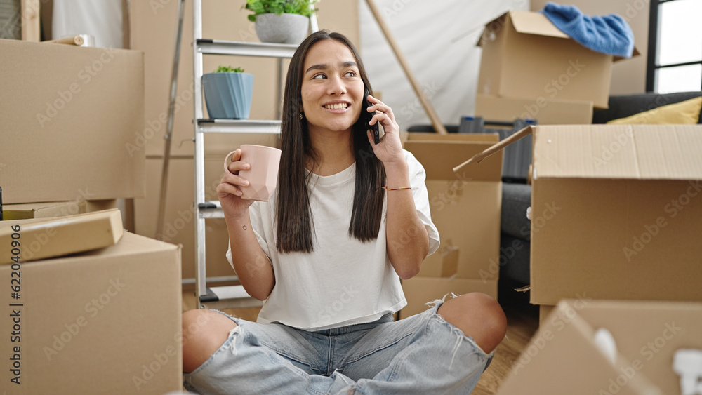 Young beautiful hispanic woman talking on smartphone drinking coffee at new home Young beautiful hispanic woman talking on smartphone drinking coffee at new home