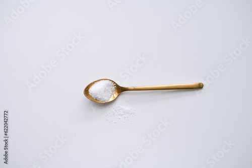 Golden spoon laying on light background with sugar. Ingredients for homemade cooking with empty space for text © Olga
