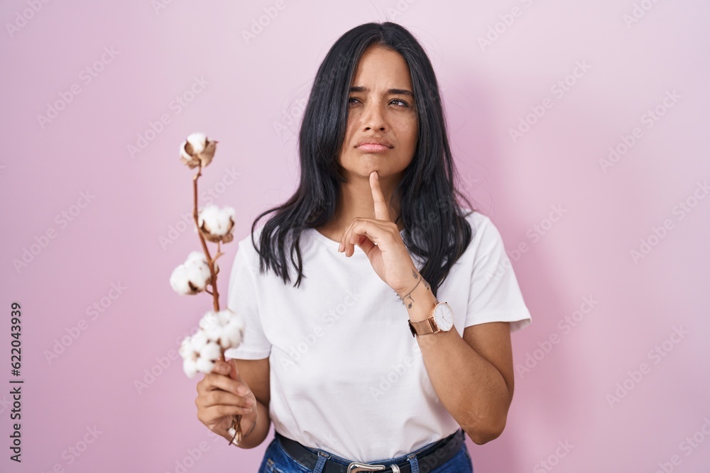 Brunette woman standing over pink background thinking concentrated about doubt with finger on chin and looking up wondering Brunette woman standing over pink background thinking concentrated about doubt with finger on chin and looking up wondering