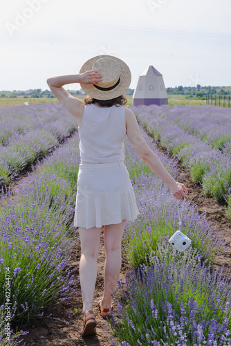 woman in straw hat standing in a lavender field and holding camera