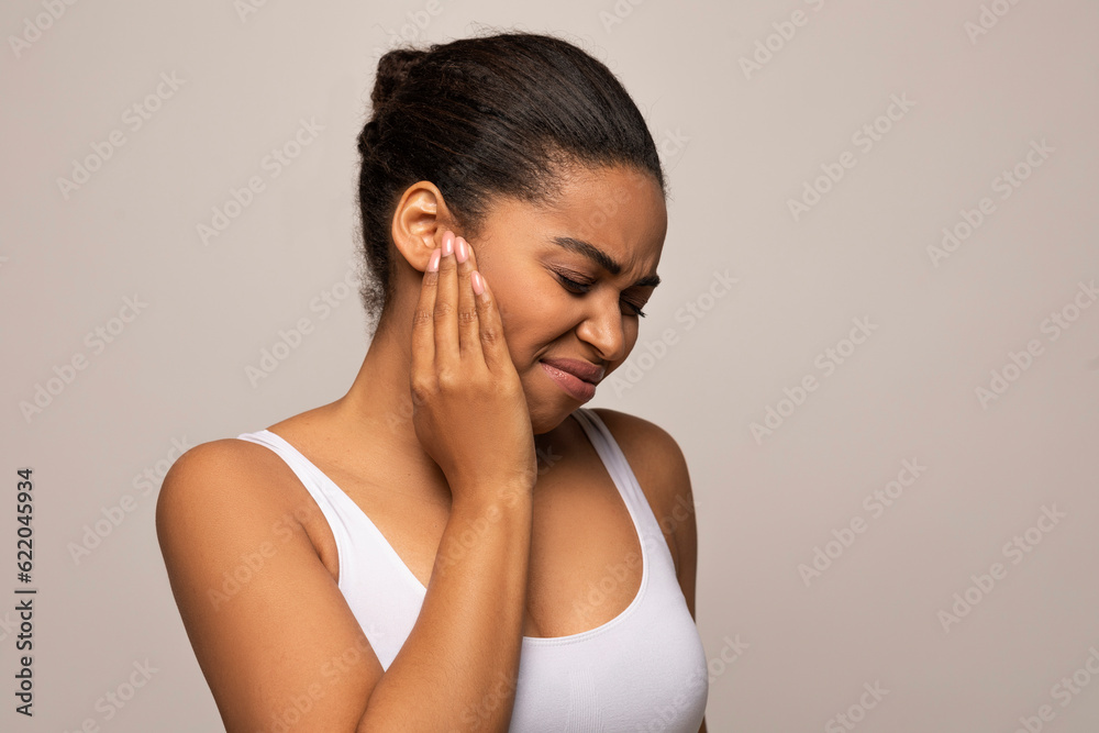 Black woman having ear pain, touching her painful head Black woman having ear pain, touching her painful head