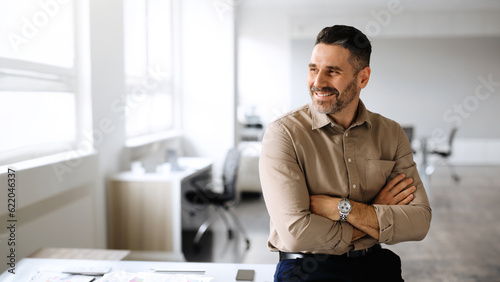 Successful middle aged businessman posing with crossed hands, looking away and smiling, copy space, panorama