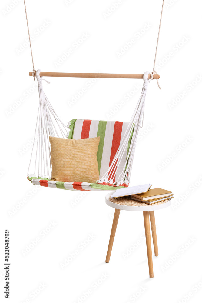 Cozy striped hammock with cushion and books on stool against white background