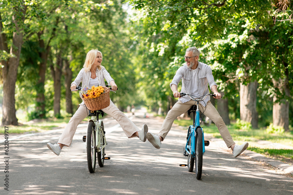 Active Retirement. Happy senior couple having fun while riding bicycles at park