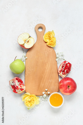 Composition with wooden board, fruits, flowers and honey on light background. Rosh hashanah (Jewish New Year) celebration