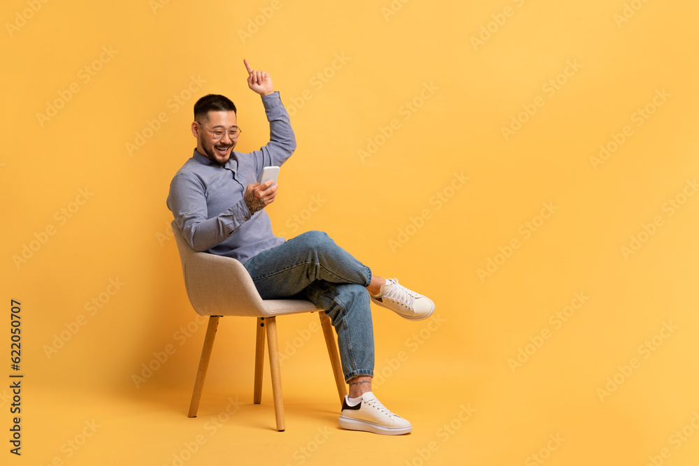 Happy Young Asian Man Playing Online Game On Smartphone And Celebrating Win