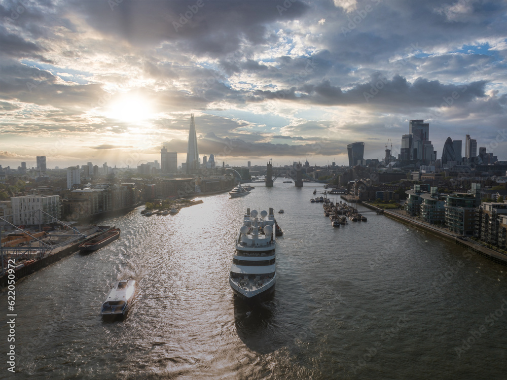 Naklejka premium Large cruise ship going through London under the Tower Bridge. Visiting center of London. Tower bridge lifting up to let the ship enter London city center.