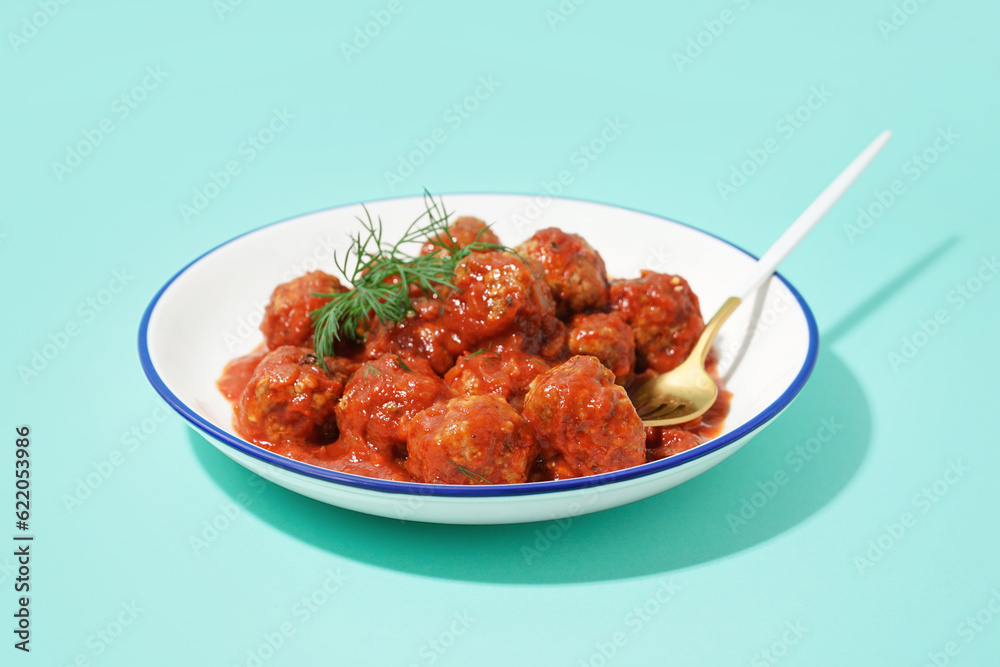 Bowl of tasty meat balls with tomato sauce and dill on blue background Bowl of tasty meat balls with tomato sauce and dill on blue background