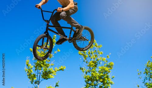 bmx rider shirtless jumping on a blue sky